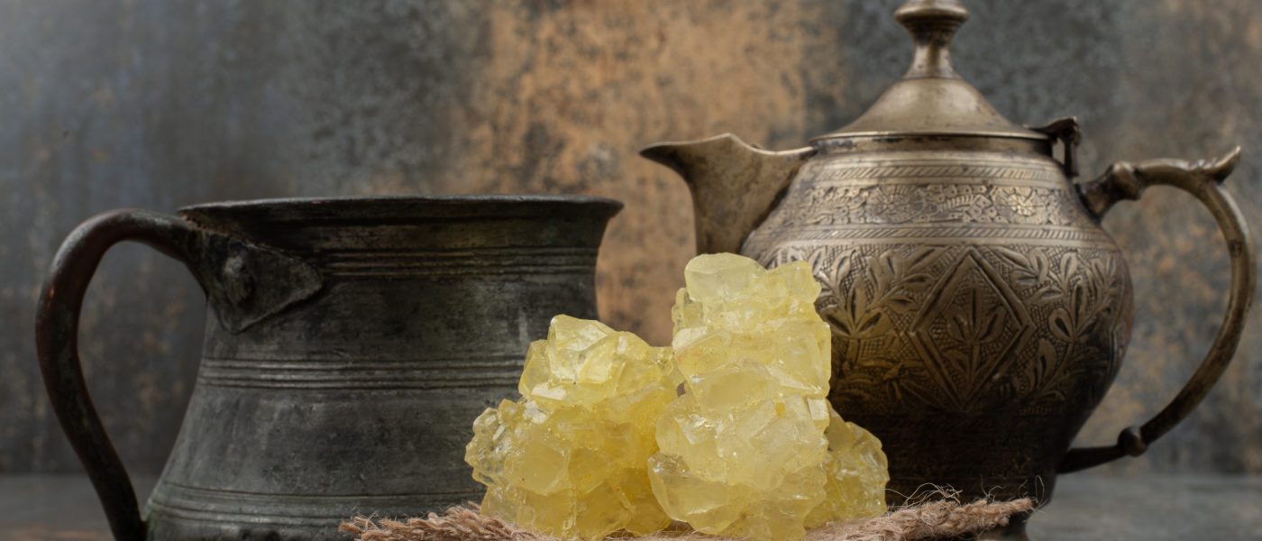Two ancient kettles with slices of sweet sugar on marble background. High quality photo